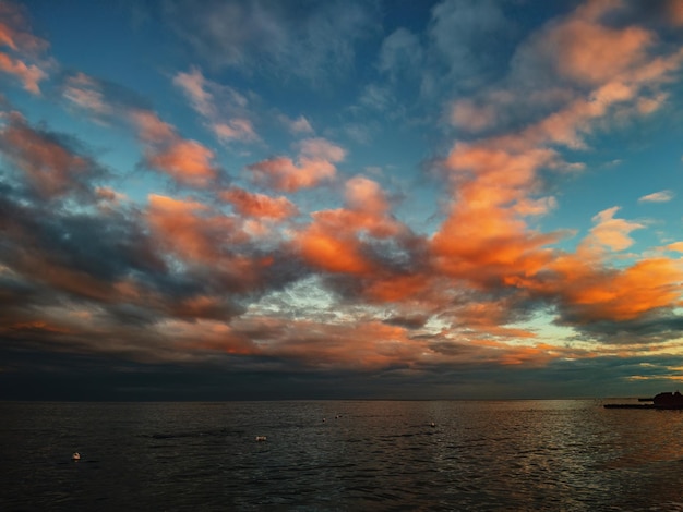 Pôr do sol à beira-mar com nuvens orangered