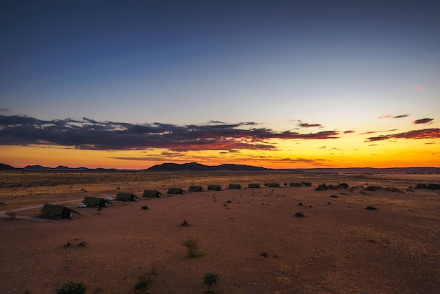 Pôr do sol acima de pequenos chalés de uma pousada no deserto perto de Sossusvlei na Namíbia