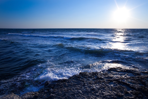 Pôr do sol azul lindo e pedras de água ao longo da costa rochosa do Mar Negro na Crimeia num dia de verão