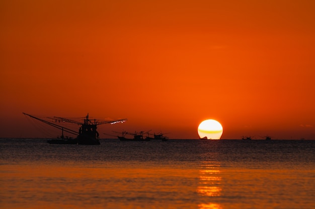 Por do sol bonito com barco e mar de pesca.