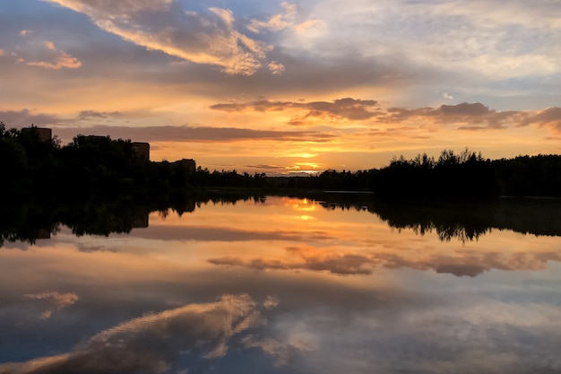 Pôr do sol colorido de verão no lago com nuvens refletidas na água