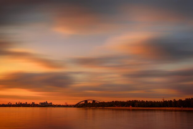 Pôr do sol colorido dramático sobre o rio Dnipro em Kiev, Ucrânia, fundo de viagens com longa exposição