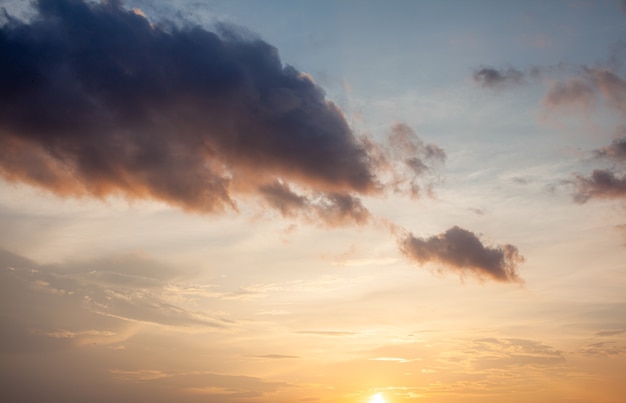 Pôr do sol colorido ou nascer do sol no céu. O céu e as nuvens são pintados em cores diferentes de laranja, amarelo e azul.