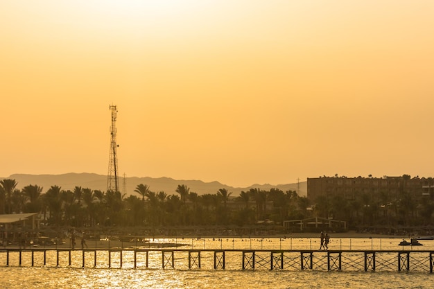 Pôr do sol com palmeiras um cais e paisagem no egito