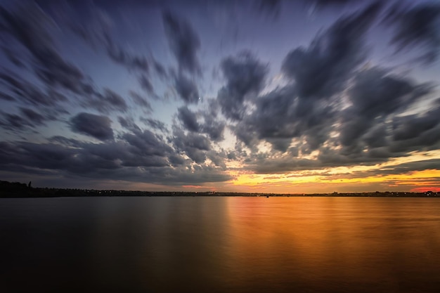 Pôr do sol de longa exposição sobre o lago Nuvens turvas e água
