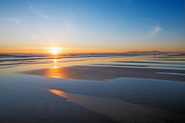 Foto pôr do sol do oceano atlântico com ondas na praia da fonte da telha portugal