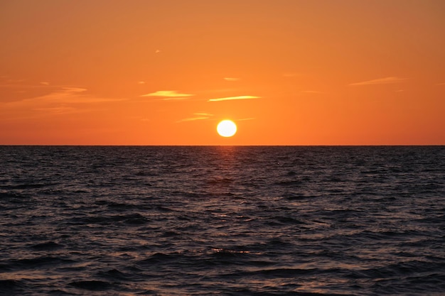 Pôr do sol do oceano Grande sol branco no dramático fundo do céu brilhante nuvem suave da noite sobre a água escura do mar