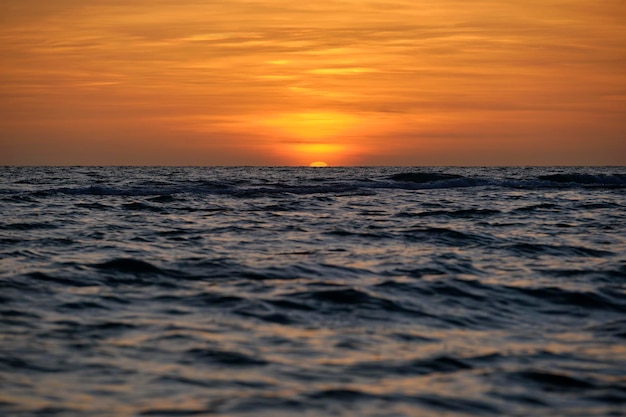 Pôr do sol do oceano Grande sol branco no fundo do céu brilhante dramático horizonte suave da noite sobre a água escura do mar