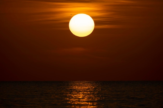 Pôr do sol do oceano Grande sol branco no fundo do céu brilhante dramático horizonte suave da noite sobre a água escura do mar