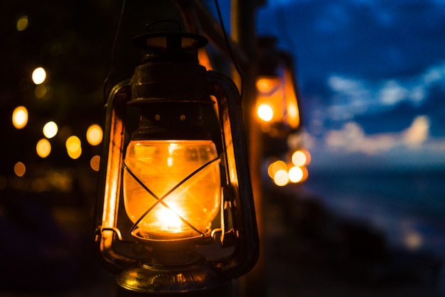 Pôr do sol em uma praia de ilha com lanternas iluminando a cena