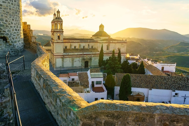 Pôr do sol espetacular sobre as montanhas com a velha igreja e as casas brancas de Olvera em Cádiz