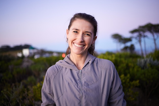 Pôr do sol feliz e retrato de uma mulher em um parque durante o crepúsculo para paz, calma e zen Caminhada de aventura e rosto de uma garota em uma caminhada para exercícios aeróbicos de verão e relaxamento durante o amanhecer na natureza