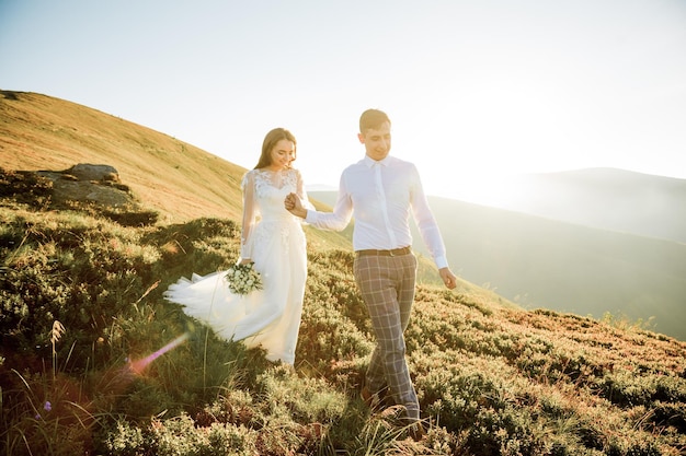 Pôr do sol ilumina colina de montanha onde o casal de noivos caminha