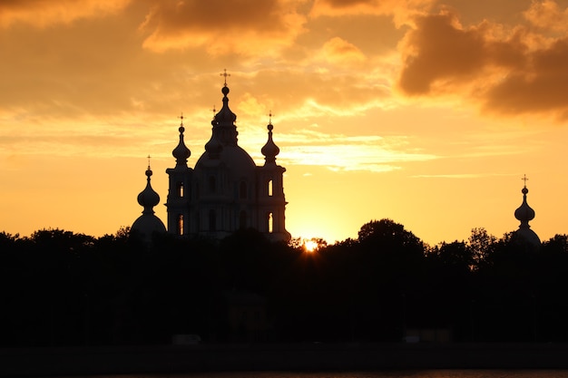 Pôr do sol laranja com igreja escura no horizonte