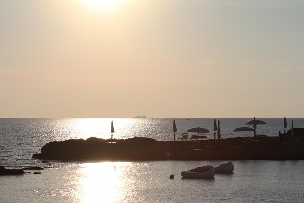 Pôr do sol na bela baía com praia de pedra e camas rosa flutuantes