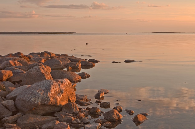 pôr do sol na costa do mar Báltico na estônia na cidade de haapsalu com rochas, mar calmo e céu rosa