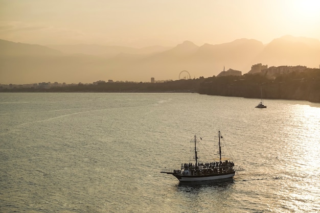 Pôr do sol na costa mediterrânea no navio da turquia no mar com turistas no fundo do ouro su ...