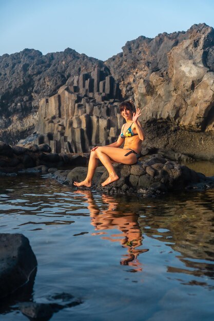 Foto pôr do sol na ilha el hierro, nas ilhas canárias, retrato de uma turista tomando banho na piscina natural de charco azul