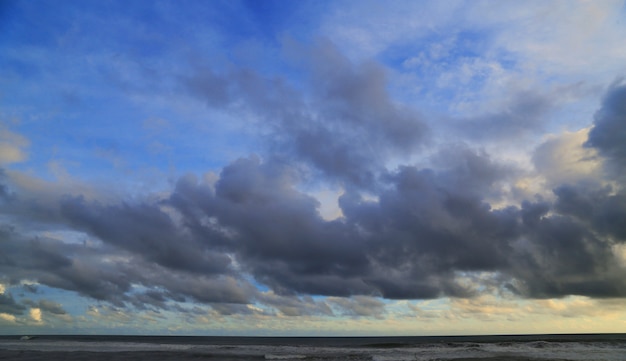 pôr do sol na praia com o céu cheio de nuvens