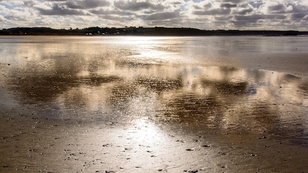 Pôr do sol na praia com reflexos na areia