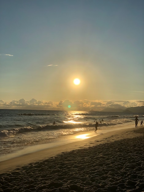 Pôr do sol na praia da Barra da Tijuca, no Rio de Janeiro, Brasil. Mar com ondas calmas.