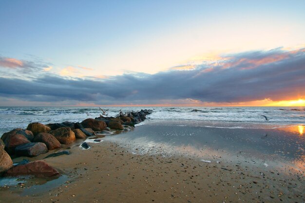 Pôr do sol na praia na Dinamarca Quebra-mar de pedra atingindo o Mar do Norte