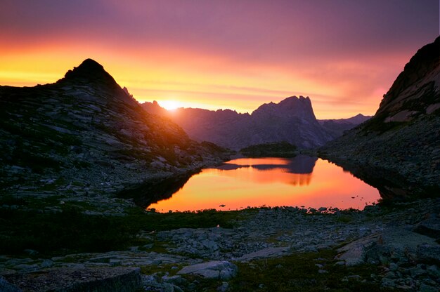 Pôr do sol nas montanhas perto do lago. luz do sol refletida no topo das montanhas