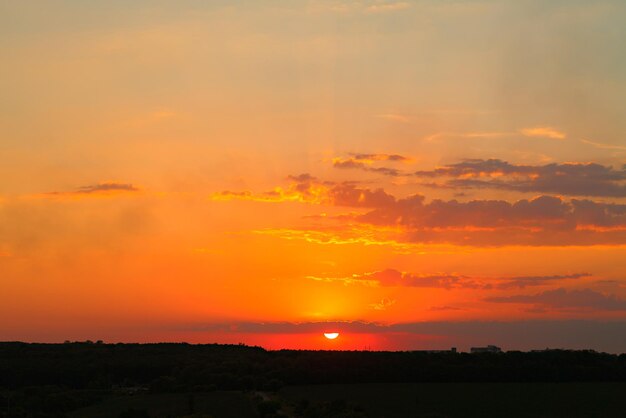 Pôr do sol natural sobre o campo escuro ou floresta Céu dramático brilhante e solo escuro à noite ao pôr do sol