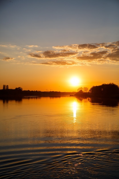 Pôr do sol no lago, o sol se põe atrás das árvores e belos reflexos na água