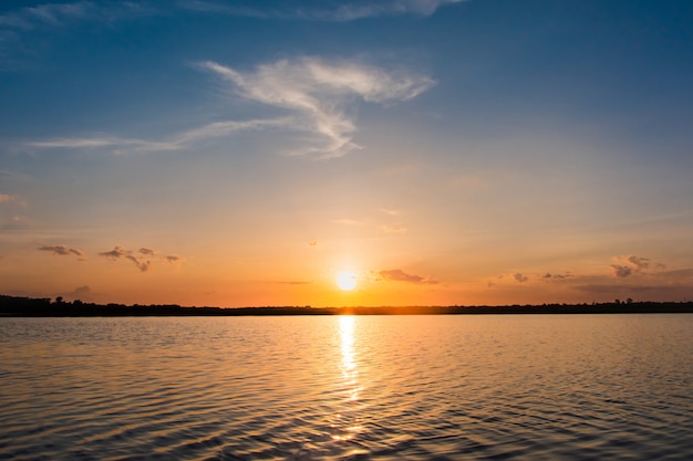 Pôr do sol no lago. por do sol bonito atrás das nuvens acima do fundo excedente da paisagem do lago.