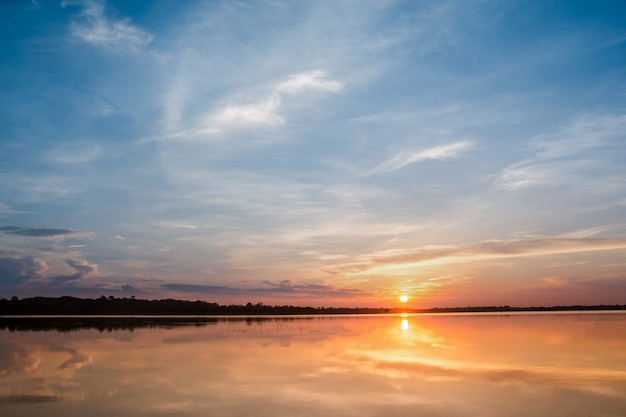 Pôr do sol no lago. por do sol bonito atrás das nuvens acima do fundo excedente da paisagem do lago.