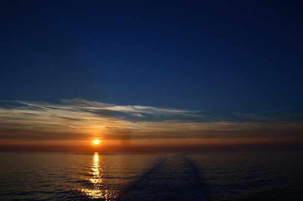 Pôr do sol no mar com rastro de navio