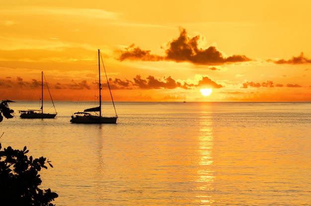 Pôr do sol no mar e silhueta de iate à vela