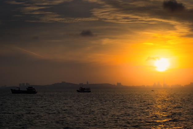 Pôr do sol no mar. Silhueta da cidade e barco de pesca