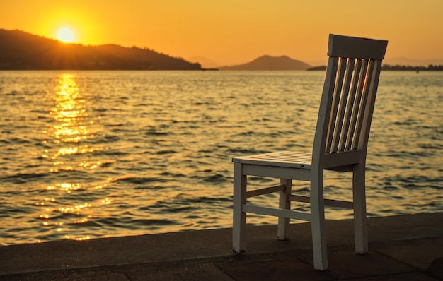 Pôr do sol no passeio à beira-mar velha cadeira em um café perto da água do mar na costa do mar Egeu quente primavera pôr do sol tempo de férias
