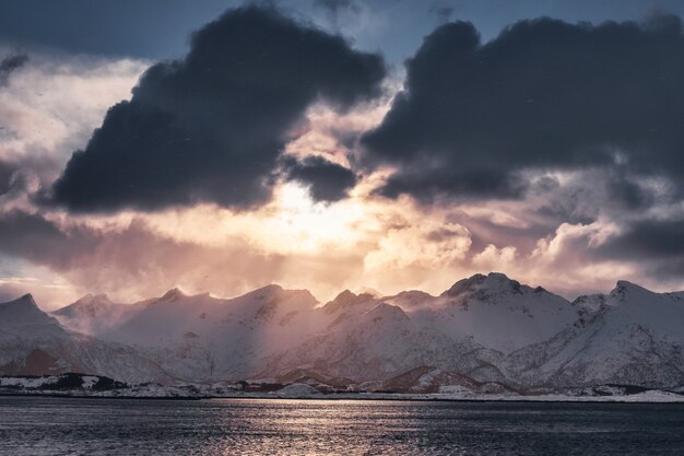 Pôr do sol nublado na cordilheira nevada na ilha de Senja, Noruega