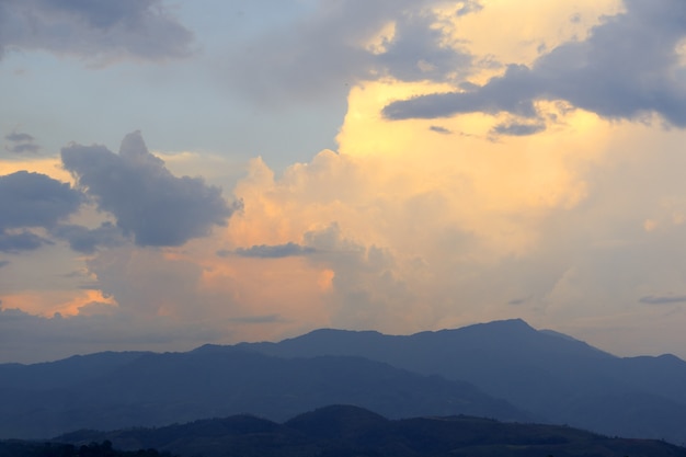 Pôr do sol nublado sobre montanhas no horizonte