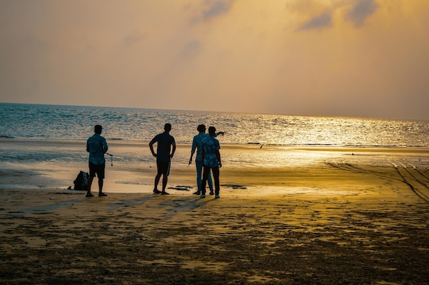 Foto pôr-do-sol numa praia com silhuetas de pessoas