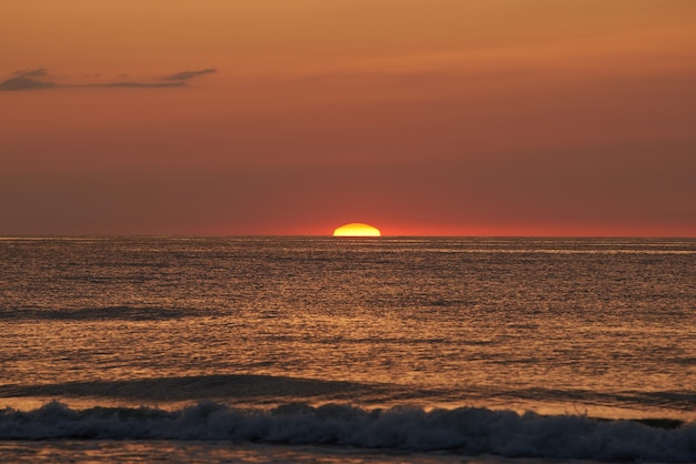 Pôr do sol radiante sobre o oceano O sol brilhante afundando no horizonte