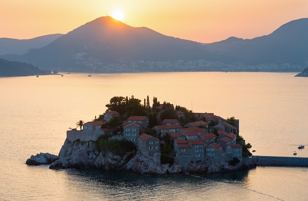 Pôr do sol rosa e vista da ilhota do mar sveti stefan de cima (montenegro, 6 quilômetros a sudeste de budva)