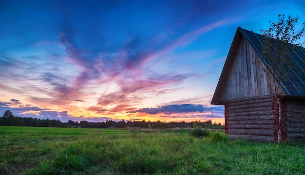 Pôr do sol rural cênico. skyline com casa de log em primeiro plano.