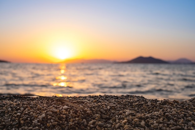 Pôr do sol sobre a baía foco seletivo nos seixos na praia ideia de fundo desfocado para protetor de tela ou publicidade