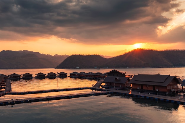 Pôr do sol sobre a montanha e resort de jangada na floresta tropical na barragem de Kanchanaburi, Tailândia