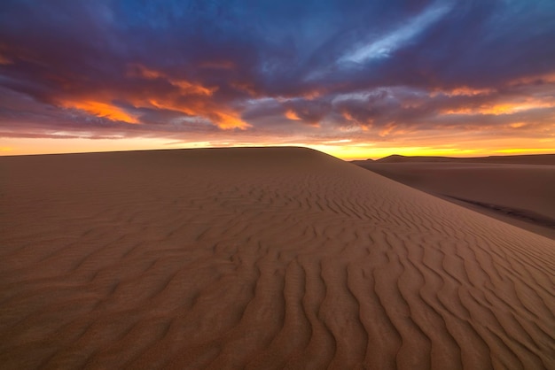 Pôr do sol sobre as dunas de areia no deserto Paisagem árida do deserto do Saara