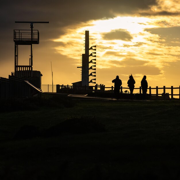 Pôr do sol sobre as falésias do mar Cantábrico com pessoas em silhueta apreciando as vistas das Astúrias