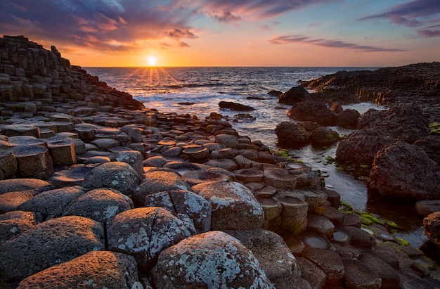 Pôr do sol sobre colunas de basalto calçada dos gigantes, condado de antrim, irlanda do norte