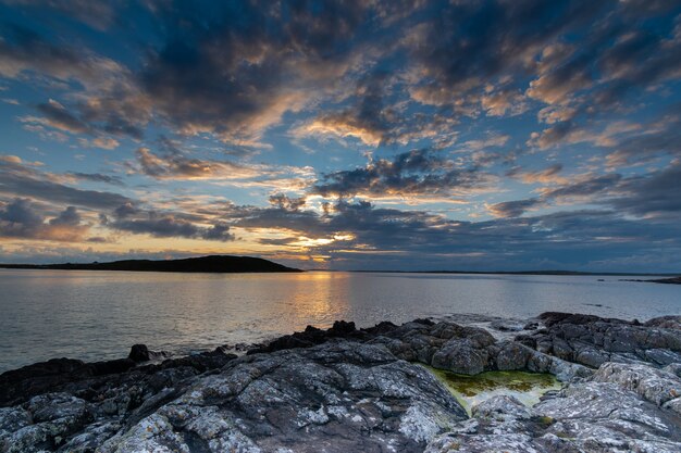 Pôr do sol sobre o horizonte do oceano em uma noite de verão quente perto da estrada do céu em connemara.