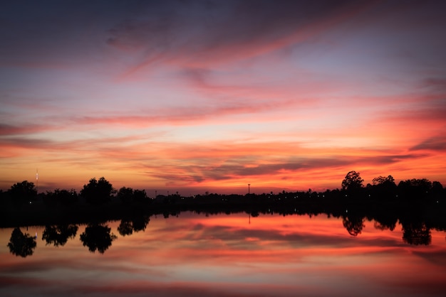 Pôr do sol sobre o lago com céu laranja vermelho.