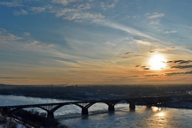 Pôr do sol sobre uma ponte rodoviária sobre o rio