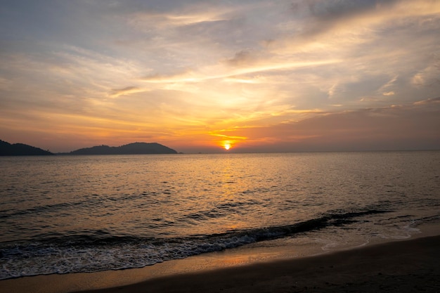 Pôr do sol tropical com ondas do mar ao longo da praia